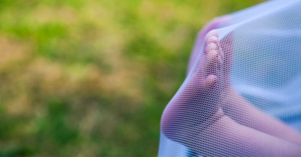 Baby feet behind a bug net outdoors How to Protect Your Kids from Mosquito Bites a post by Raising Bliss