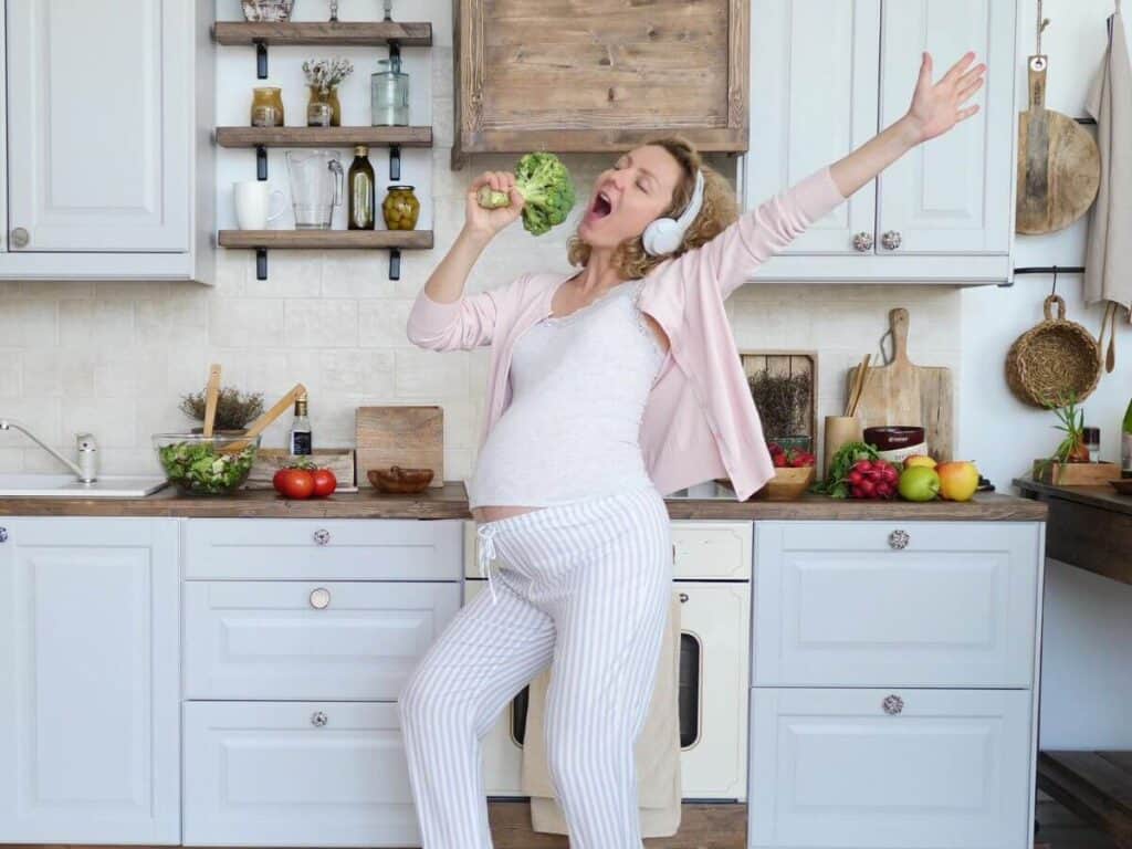 A mom singing in the kitchen using broccoli as a microphone.  How to stop yelling at your kids - sing and dance when you feel frustrated.